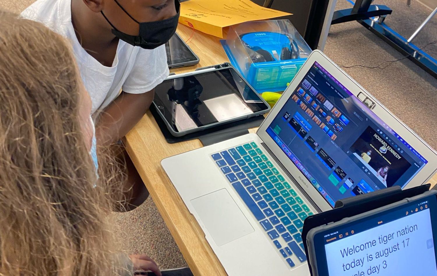 Student gather around a laptop to edit the news