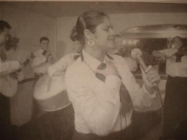 Black and white image of mariachi band performing behind female singer