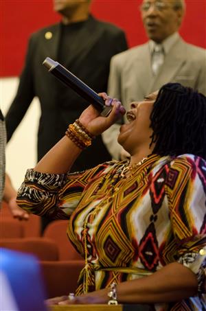 A woman sings into a microphone at church