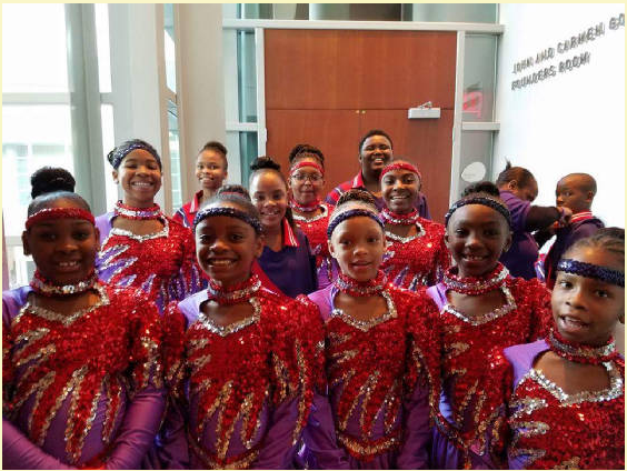 A group of drill and step performers pose in sparkly red and purple costumes
