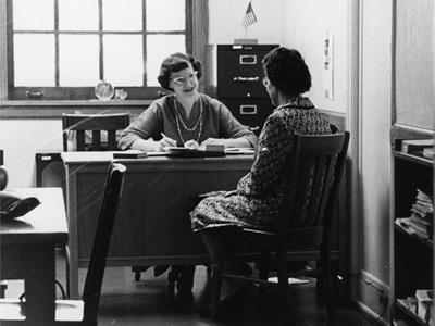 Dorothy Patach speaks with a woman sitting at a desk